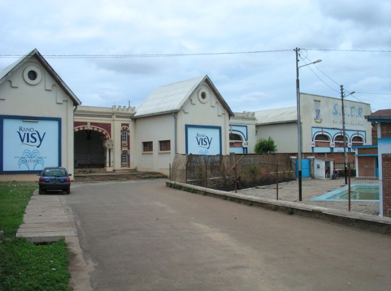 Photo 5 : La source Rano Visy (novembre 2011). Le pavillon, dont la buvette est fermée au public, est englobé dans un ensemble de bâtiments de l’usine d’embouteillage de la Société d’Embouteillage des Eaux de source de Ranovisy (SEER). À droite, la piscine en partie alimentée par la source